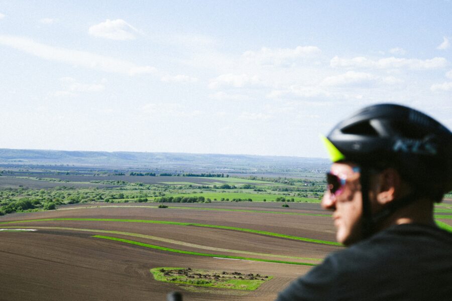 Людина їде велосипедом серед полів
